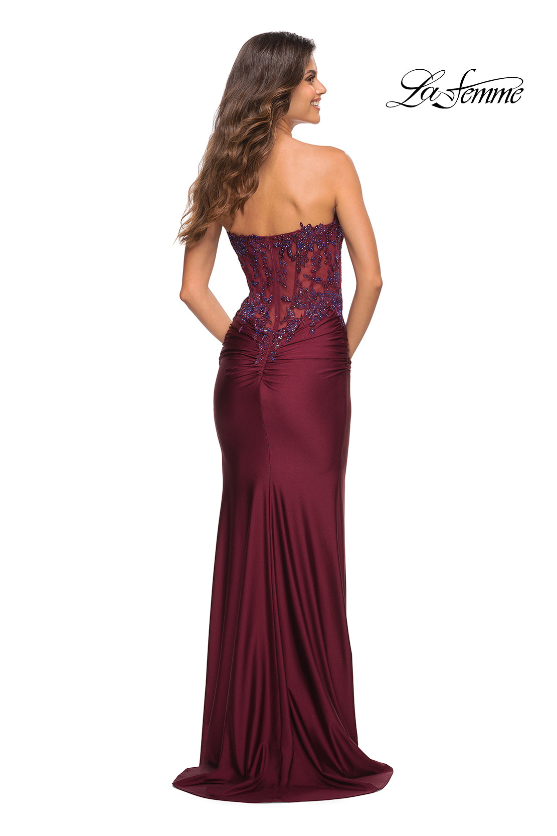 A woman faces away in the Sheer-Lace-Bodice La Femme Strapless Prom Dress, featuring elegant lace details on the bodice. The 