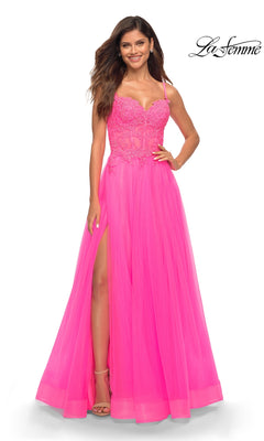 A woman smiles in the La Femme Neon Pink Long Ball Gown with Lace, featuring thin straps and a high slit. The La Femme logo is displayed in the top right corner.