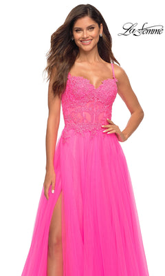 A woman smiles confidently in the La Femme Neon Pink Long Ball Gown with Lace, featuring a slit skirt and lace bodice. The La Femme logo appears in the top right corner.
