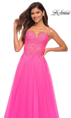 A woman wears the La Femme Neon Pink Long Ball Gown with Lace, featuring a lace bodice and tulle skirt, posed against a plain white background.