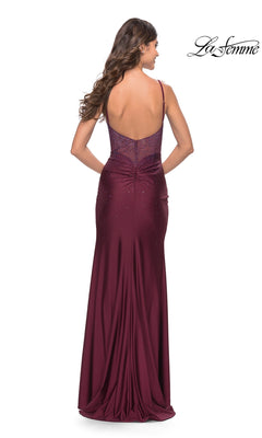 A woman with wavy brown hair models the La Femme Embellished Long Sweetheart Prom Dress—a sleeveless, floor-length maroon jersey gown with a low back and subtle embellishments. The La Femme logo appears in the top right corner.