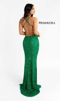 A woman stands facing away in the Open-Back Bright Long Sequin Prom Dress 3291B, a floor-length, backless green gown with thin crisscross straps and "PRIMAVERA" on the right side.