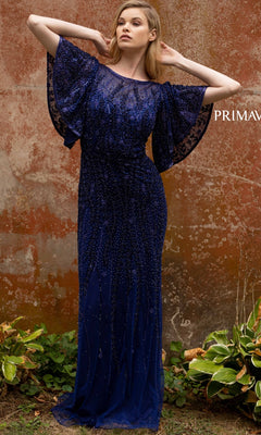 A woman stands outdoors by a weathered wall, wearing the elegant Short-Sleeve Beaded Long Prom Dress 3681. This floor-length navy gown features flutter sleeves and delicate detailing, with green plants at her feet.