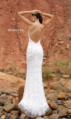 A woman in a Primavera 3731 Sequin-Print Long Formal Prom Dress stands on rocky ground, arms raised, against a reddish-brown earth backdrop.