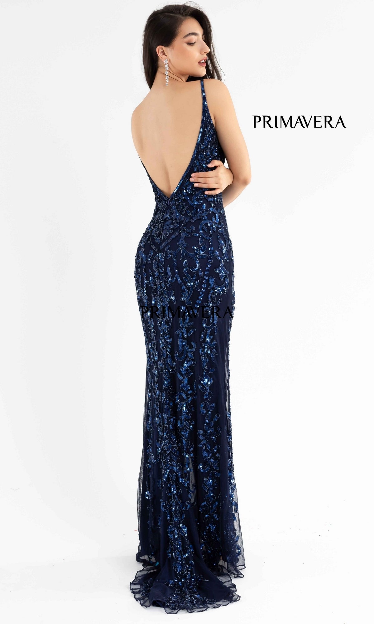 A woman stands facing away in the navy Open-Back Primavera 3749 Long Sequin Prom Dress. The word 