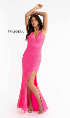 A woman poses in the Bright Sequin-Print Long Prom Dress 3792B, a sleeveless fitted hot pink gown with a high slit, textured sequin-print fabric, V-neckline, and thin straps; "PRIMAVERA" text appears on the plain white background.