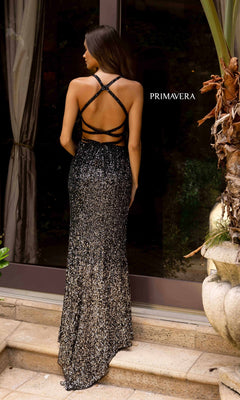 A woman stands on steps facing away, wearing the Primavera 3922 Sequin Ombre Long Prom Dress—a long, backless black and silver gown with crisscross straps. The word "PRIMAVERA" appears in the background.