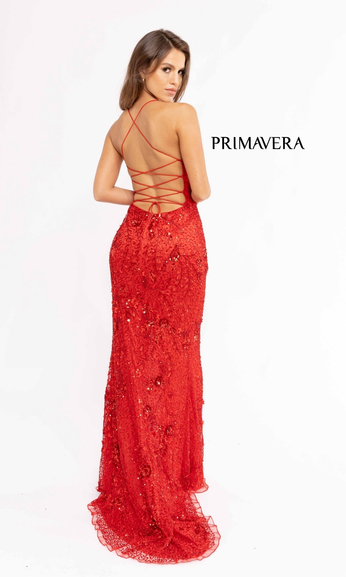 A woman in the Strappy-Back Sequin Long Prom Dress 3931, a floor-length red gown with long sequins and an open strappy back, faces away from the camera. 