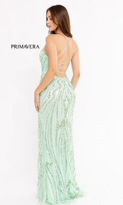 A woman in the Strappy-Back Long Sequin Prom Dress 3958, a light green floor-length gown with sequins and an open strappy back, stands against a plain white background. "PRIMAVERA" is displayed to the left.
