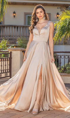 Woman wearing the Long Satin Classic A-Line Prom Dress in champagne, featuring a deep V-neckline, high slit, and flowing skirt, standing outdoors by a decorative railing and greenery.