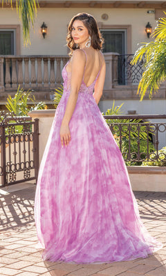 A woman stands outdoors in the Tie-Dye Prom Ball Gown with Sheer Sides—a flowing, sleeveless pink and purple formal dress with a low back—looking over her shoulder.