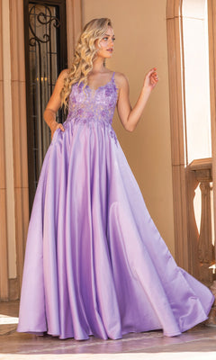 Dressed in the A-Line Long Prom Ball Gown: Dancing Queen 4326—a lavender gown with lace bodice detailing—a woman stands before an arched stone building, embodying elegance and grace.
