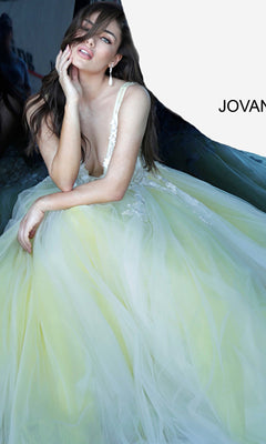 A woman in a Jovani Tulle Prom Ball Gown with Floral Appliques, pale yellow and adorned with delicate flowers, poses seated with one hand on her face before a backdrop showing partial "JOVAN" text.