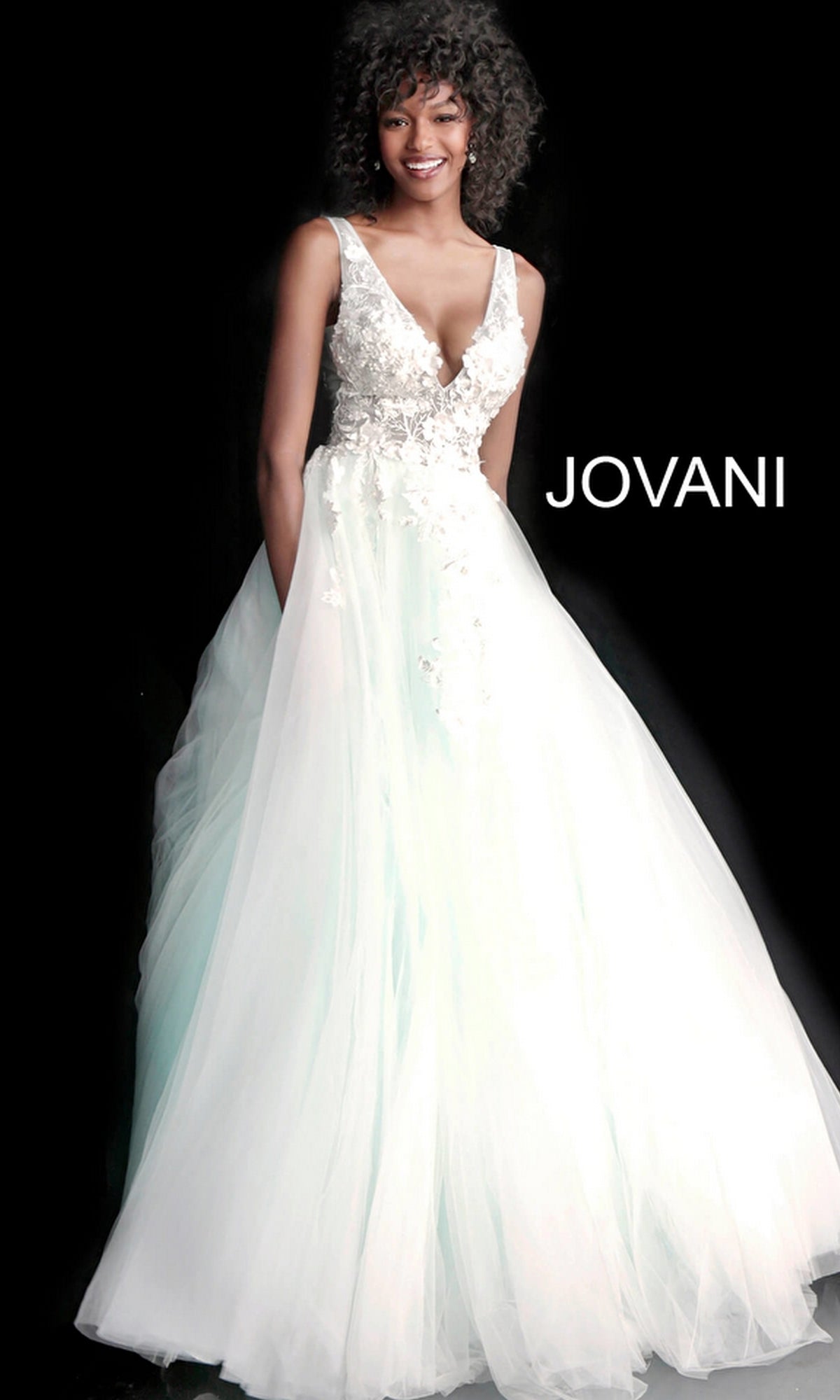 A woman wears the Jovani Tulle Prom Ball Gown with Floral Appliques, featuring a floor-length white skirt, fitted embroidered bodice, deep V neckline, and delicate floral details. 