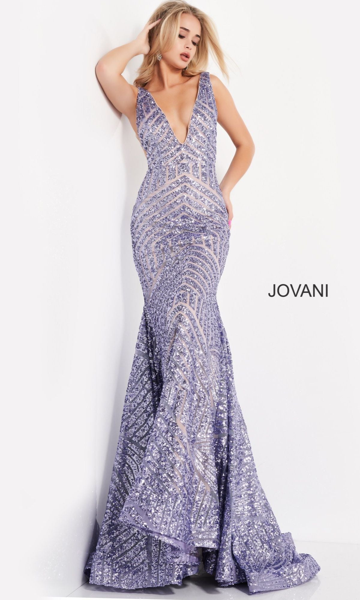 A woman poses against a white wall wearing the Jovani Plus-Size Mermaid Prom Dress with Sequins, a sleeveless, floor-length lavender gown featuring a deep V-neckline. The word 