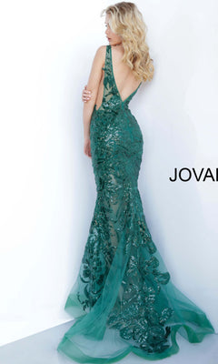 A blonde woman wears the Jovani Embroidered Long Prom Dress with Sequins—an emerald green, backless evening gown featuring a long, sheer train—posing against a white background.