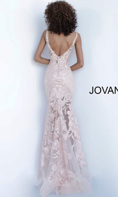 Woman with curly hair wears a pale pink, floor-length Jovani Plus-Size Sheer Prom Dress with sequins and a deep V-back, standing against a plain light background.
