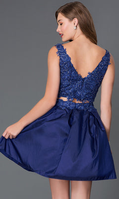 Woman in a Two-Piece Lace-Bodice Short Party Dress with a sleeveless top and cutout back, featuring deep blue sequins, standing against a plain gray background.
