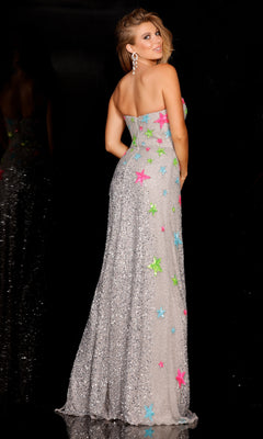 A woman poses with her back to the camera in the Neon Star Print Strapless Sequin Prom Dress 625, a floor-length gown adorned with colorful neon stars, set against a dark background.