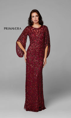 A woman poses in the Long Bell Sleeve Beaded Evening Gown 9713—floor-length, burgundy, and adorned with beads—featuring flowing bell sleeves against a plain gray background. "PRIMAVERA" is displayed on the left.