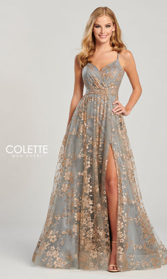 A woman poses in the Colette Gold and Pewter Long Prom Dress CL12006, a floor-length A-line gown with gold embroidery, glitter floral prints, deep V-neckline, thin straps, and a high leg slit against a plain background.