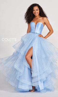 A woman stands smiling in the Colette Glitter-Tulle Layered Long Prom Ball Gown—a strapless, light blue tulle dress with sparkling details and a thigh-high slit—for an enchanting, elegant look.