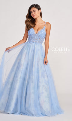 A woman stands against a plain background wearing the Pastel Long Tulle Prom Ball Gown by Colette, featuring a light blue lace bodice and sheer tulle skirt—an elegant choice for prom.