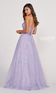 A woman wearing the Pastel Long Tulle Prom Ball Gown by Colette, featuring a lace-up back, thin straps, and a full skirt, stands facing slightly away from the camera.