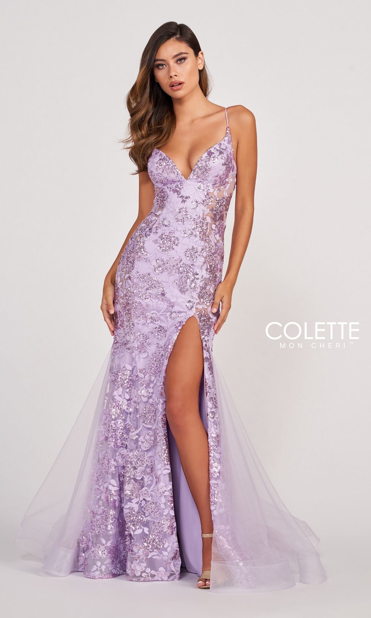 A woman wearing the Colette Long Sequin Prom Dress with Sheer Sides in lavender, featuring a thigh-high slit and thin straps, stands against a plain background.
