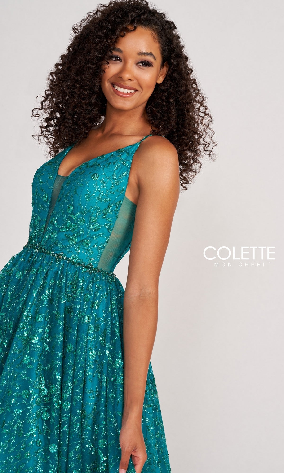 A woman smiles against a plain background, wearing the Backless Tulle Prom Ball Gown CL2016 with glitter print. The sleeveless teal dress features sequin embellishments, sheer side panels, and a full tulle skirt.