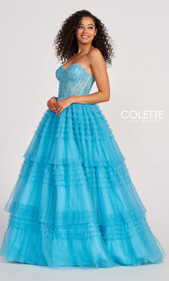 A woman in the Colette CL2017 Strapless Ruffled Prom Ball Gown with a beaded corset bodice and tulle skirt smiles against a plain light background, with the "Colette Mon Cheri" logo beside her.