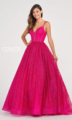 A woman poses against a plain light background in the Colette CL2018 Deep V-Neck Glitter-Lace Ball Gown—bright pink, floor-length, with a fitted bodice, spaghetti straps, and textured lace overlay.