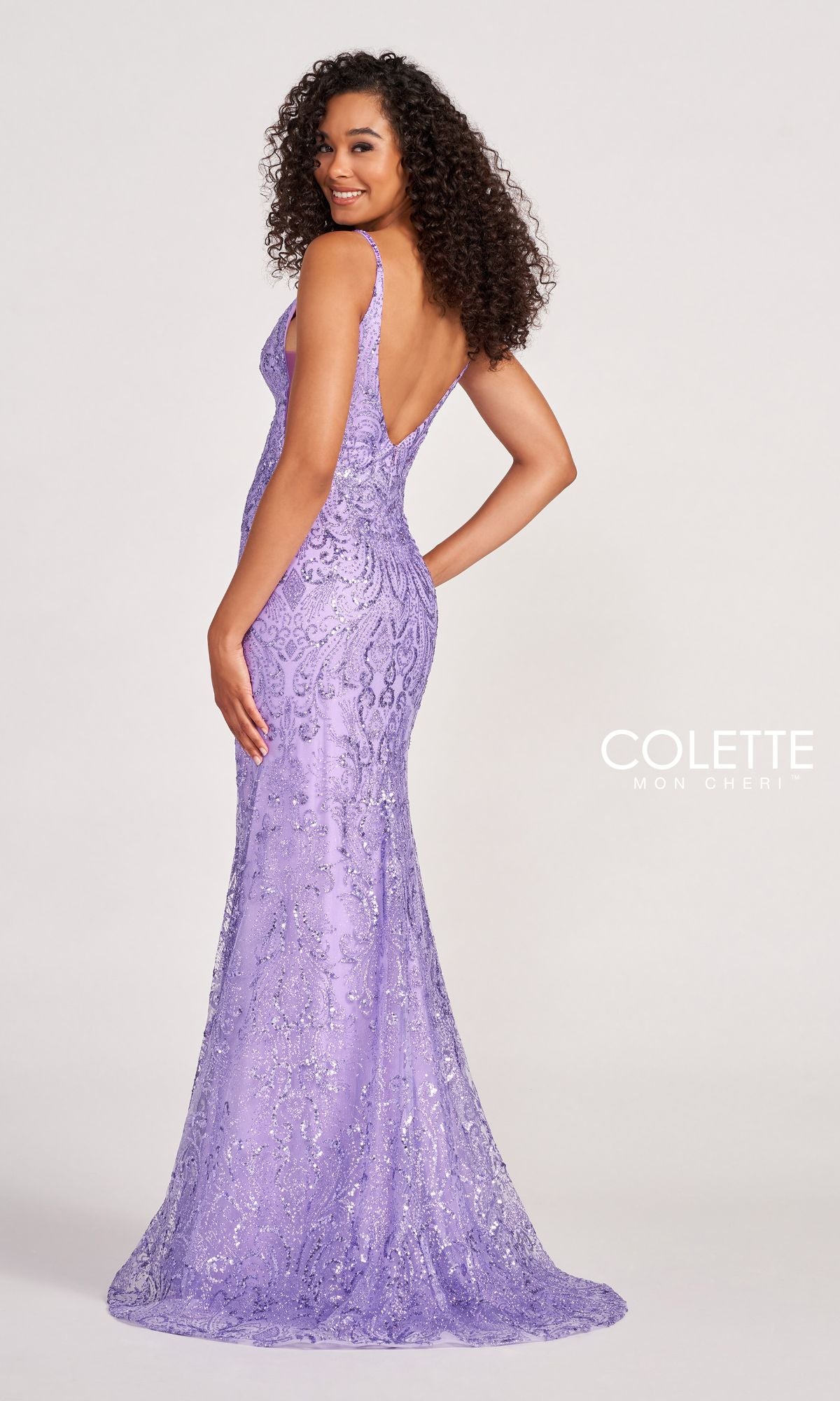 A woman poses and smiles over her shoulder in the Colette CL2019 Long Prom Dress in Glitter-Sequin, featuring a fitted, floor-length silhouette and deep V-back. The 