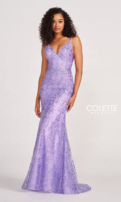 A woman stands before a plain background in the Colette CL2019 Long Prom Dress in Glitter-Sequin, a sleeveless, floor-length lavender gown with a fitted bodice, flared skirt, subtle pattern, and elegant V-neckline.