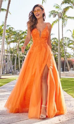 A woman stands outdoors among palm trees, wearing sunglasses, white sandals, and the Beaded Lace Long A-Line Prom Dress Colette CL2025—an orange, sleeveless, floor-length gown with a deep V-neckline and high slit.