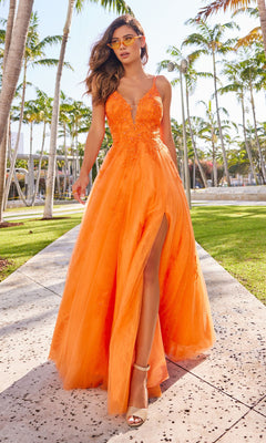 A woman wearing the Beaded Lace Long A-Line Prom Dress Colette CL2025, featuring a high slit and v-neckline, walks outdoors on a sunny day surrounded by palm trees.