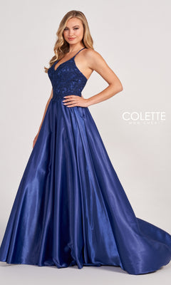 A woman stands against a plain background wearing the Colette by Daphne Satin Prom Ball Gown CL2033, featuring a floor-length royal blue satin skirt, fitted lace bodice, and spaghetti straps.