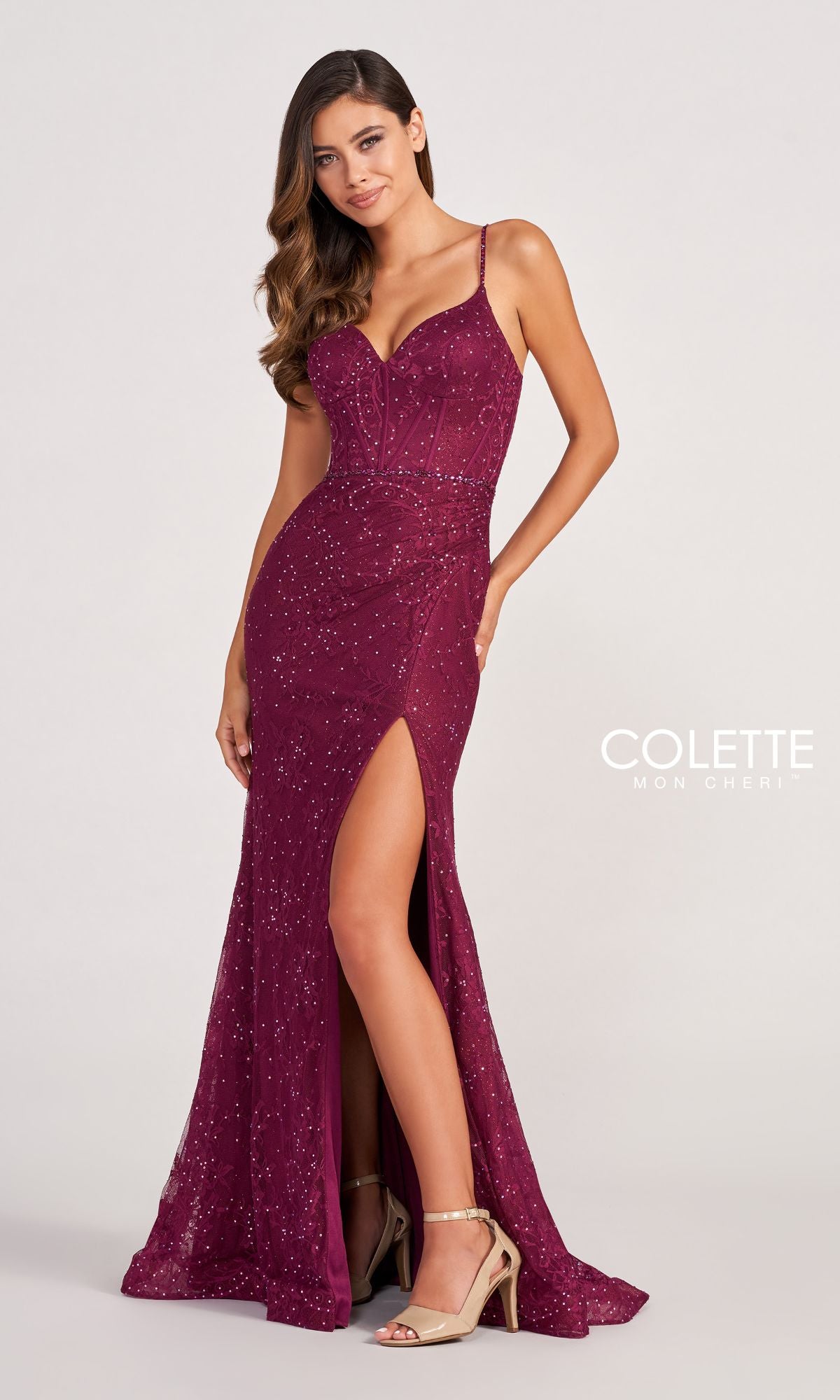 A woman poses against a plain background in the Colette CL2037 Long Lace Prom Dress with Beads, a sleeveless formal gown featuring intricate lace, sparkling beads, and a thigh-high slit, paired with strappy heels.