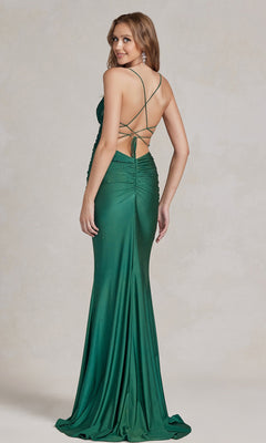 Woman wearing a Backless Prom Dress with Beaded Floral Appliques, featuring a long, fitted design in emerald green and crisscross straps, standing on a light-colored background.