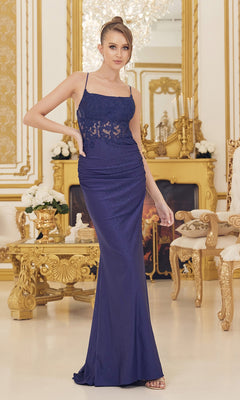 A woman wears the Backless Prom Dress with Beaded Floral Appliques, a fitted floor-length royal blue gown, as she poses in an ornate, gold-accented room with elaborate furniture and a fireplace in the background.