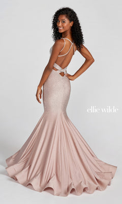 A woman poses, smiling over her shoulder in the Strappy-Back Long Beaded Ellie Wilde Formal Gown—a blush pink mermaid dress with a flared bottom, open back, crisscross straps, and elegant beaded embellishments.