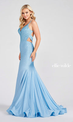 A woman stands against a plain background wearing the Strappy-Back Long Beaded Ellie Wilde Formal Gown—a light blue, sleeveless, floor-length dress with side cutouts, a flared skirt, open back, and elegant bead embellishments.