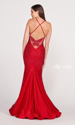 A woman faces away from the camera, wearing the Ellie Wilde Butterfly-Back Long Beaded Prom Dress—an elegant red, floor-length gown with crisscross straps and a butterfly detail on the back, set against a plain background.