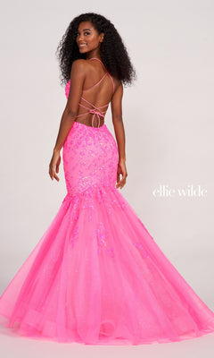 A woman wears the Ellie Wilde Glitter-Tulle Long Mermaid Prom Gown in bright pink with sequin details and lace-up straps; the "Ellie Wilde" logo is visible on the right side.