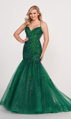A woman poses against a plain light background wearing the Ellie Wilde Glitter-Tulle Long Mermaid Prom Gown with thin straps in sparkly green.