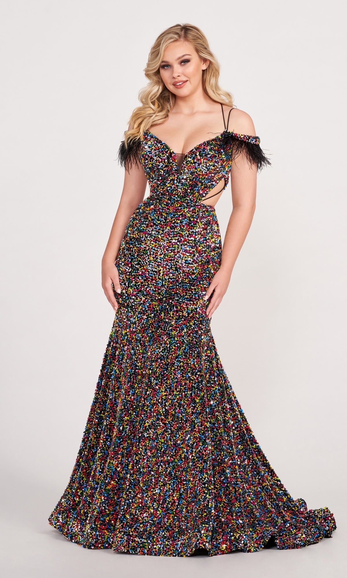 A woman poses against a plain background in the Long Sequin Cut-Out Prom Dress with Feathers—a fitted, floor-length mermaid gown featuring multicolored sequins, feather-trimmed straps, and bold cutout sides.