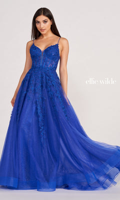 A woman models the Sheer-Corset Long Lace Prom Ball Gown EW34036, a sleeveless floor-length royal blue dress with tulle details, against a plain background. The text "Ellie Wilde" appears on the right.