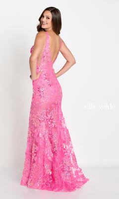 A woman models the Ellie Wilde Sheer-Skirt Long Prom Dress EW34040—a floor-length, sleeveless, backless pink sequin mermaid gown with floral patterns—smiling slightly away against a plain white background. The text reads "ellie wilde.