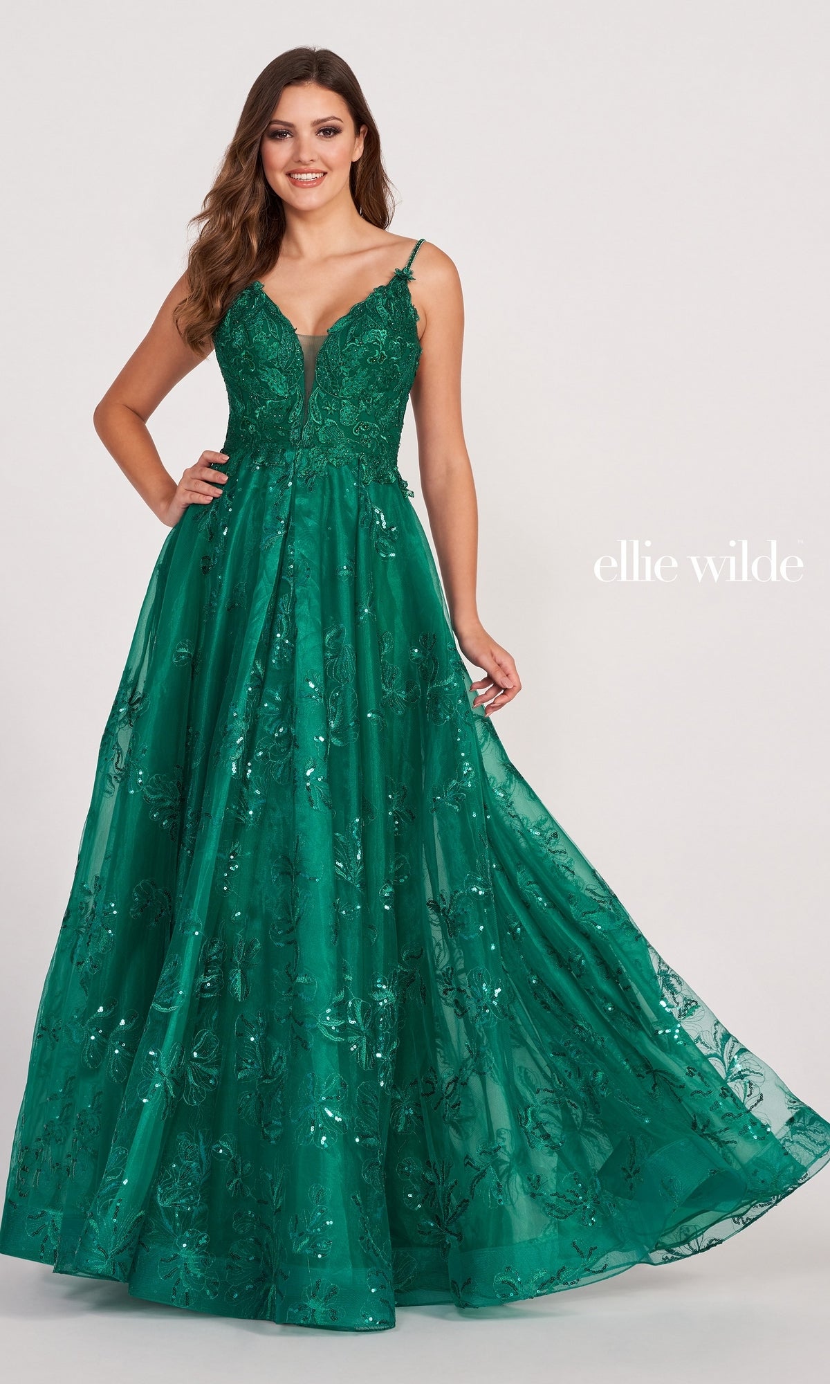 A woman models the sleeveless Tulle Embroidered A-Line Prom Dress by Ellie Wilde in deep green, featuring floral embroidery and a full tulle skirt, against a plain light background. 
