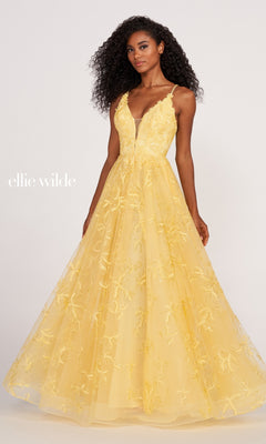A woman wears the Tulle Embroidered A-Line Prom Dress by Ellie Wilde, a sleeveless, floor-length yellow gown with floral embroidery, a fitted bodice, and a full, flowing skirt, standing against a plain background.